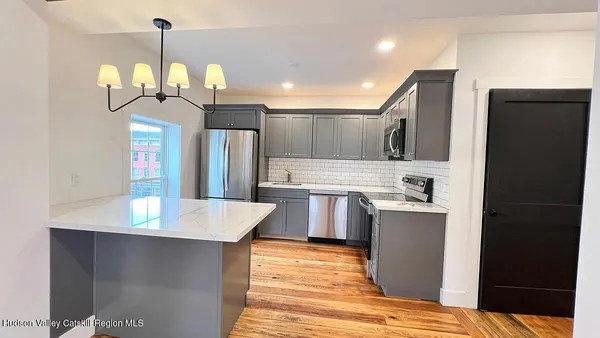 a kitchen with kitchen island granite countertop a refrigerator a stove a sink dishwasher and a dining table with wooden floor