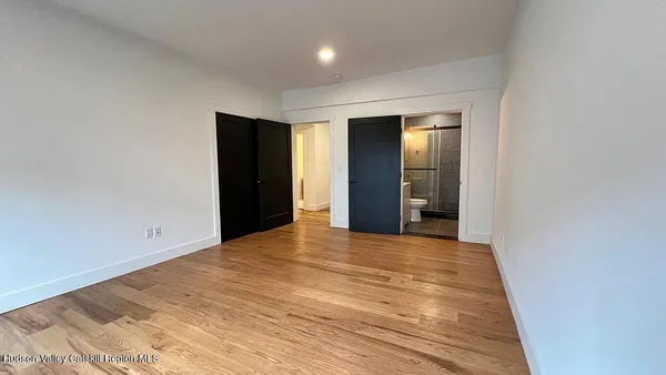 a view of an empty room with wooden floor and closet
