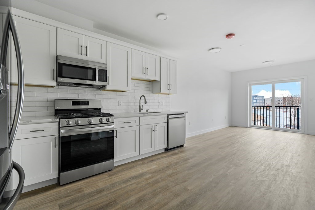 1133 North Shore Road, Unit 205 Revere, MA 02151 - Photo 7 of 20 a kitchen with stainless steel appliances white cabinets a sink and a stove