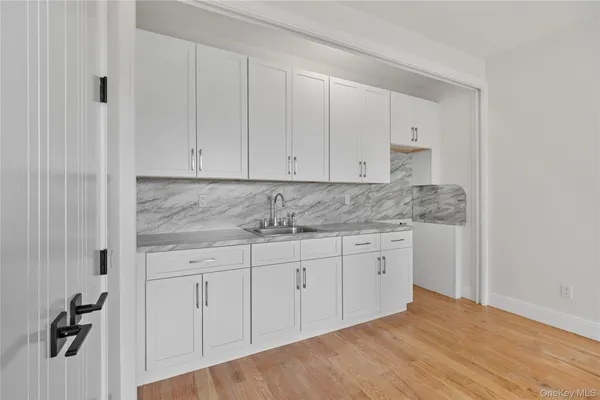 a bathroom with granite countertop white cabinets and a sink