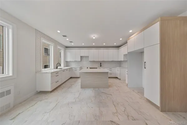 a large white kitchen with kitchen island a sink stainless steel appliances and cabinets