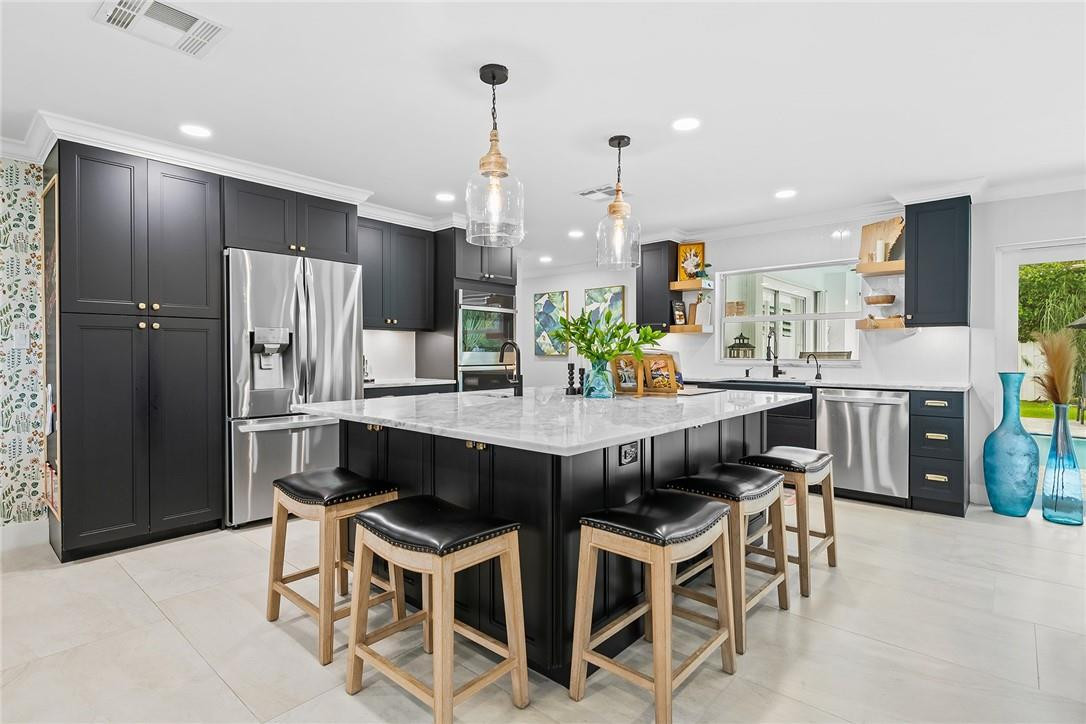 1621 Northwest 10th Street Boca Raton, FL 33486 - Photo 3 of 25 a kitchen with stainless steel appliances kitchen island granite countertop a dining table chairs and a refrigerator