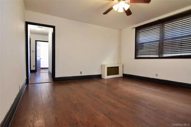 an empty room with wooden floor chandelier and windows