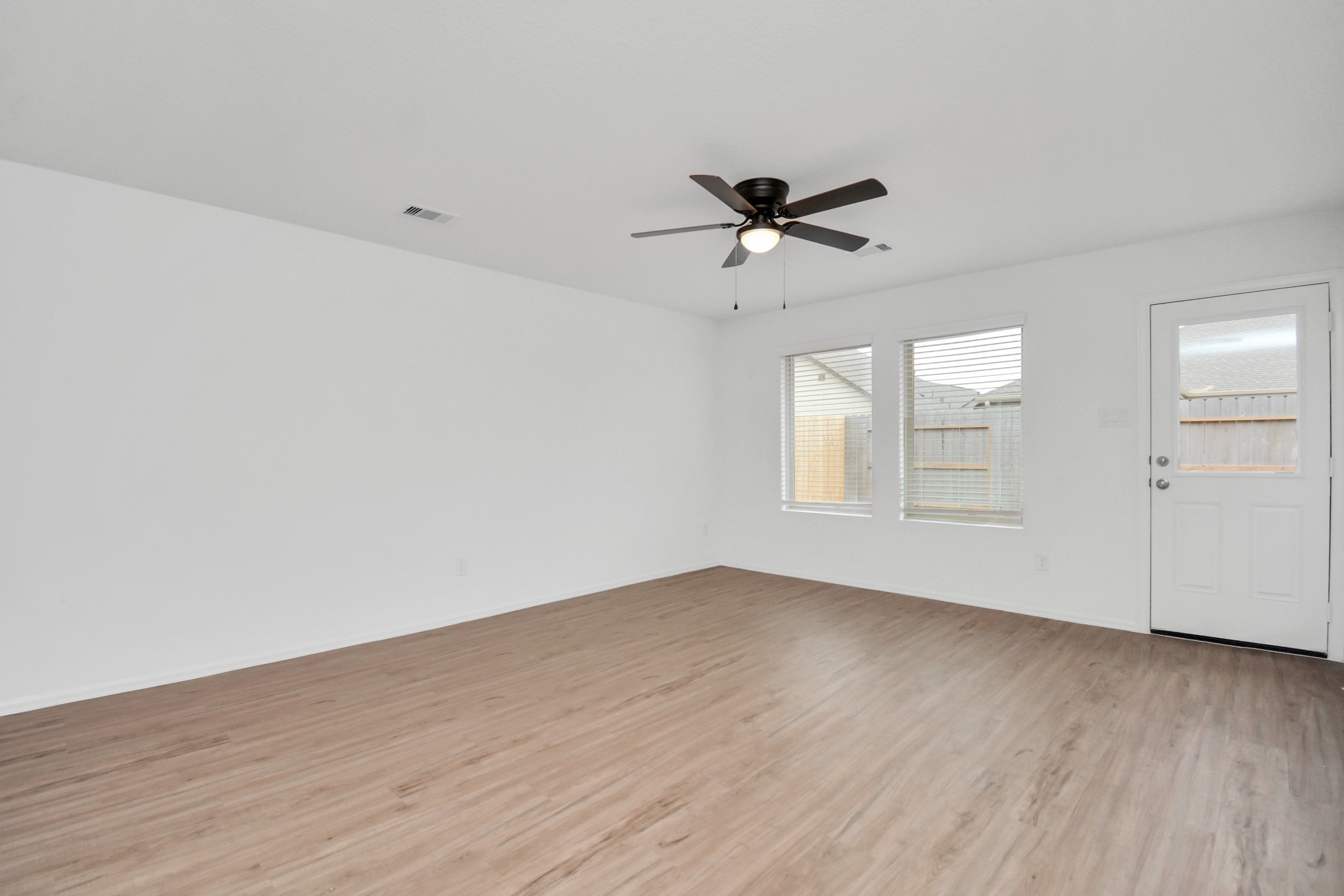 27023 Rimini Point Drive Katy, TX 77493 - Photo 5 of 15 an empty room with wooden floor fan and windows