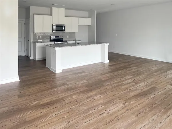 a kitchen with stainless steel appliances a sink a stove top oven and wooden floors