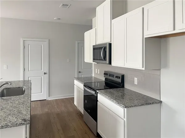 a kitchen with granite countertop a sink a stove and cabinets