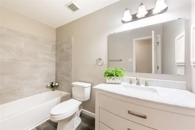 a bathroom with a granite countertop toilet a sink and a bathtub