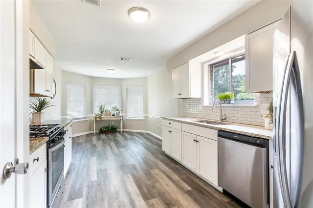 a kitchen with a sink appliances cabinets and a window