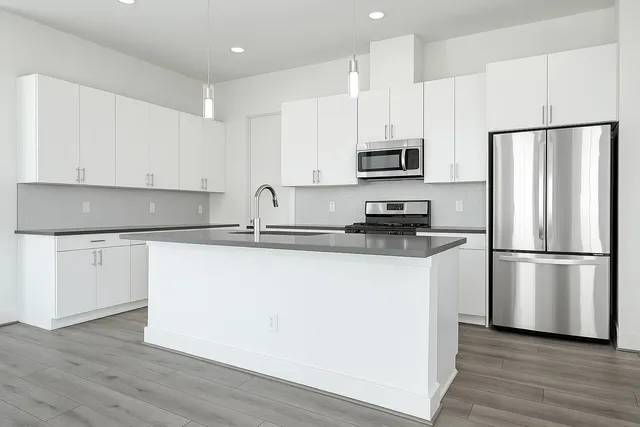 a kitchen with a refrigerator a stove top oven and white cabinets