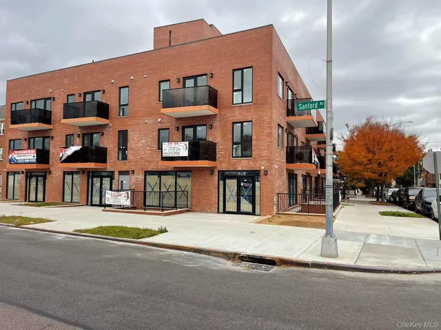 a front view of a building with streets and trees