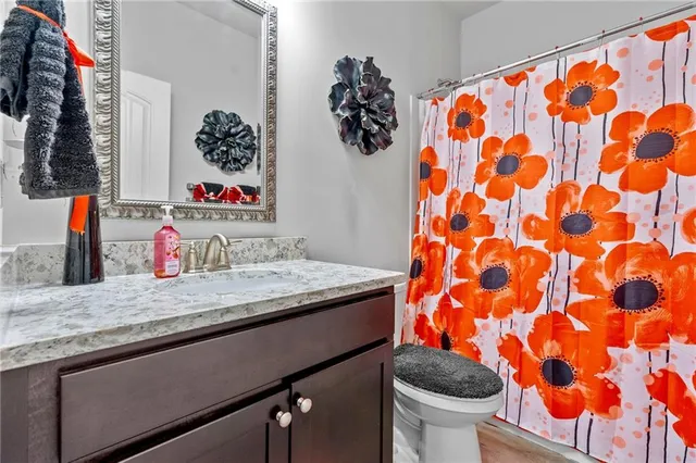 a bathroom with a granite countertop sink and a toilet