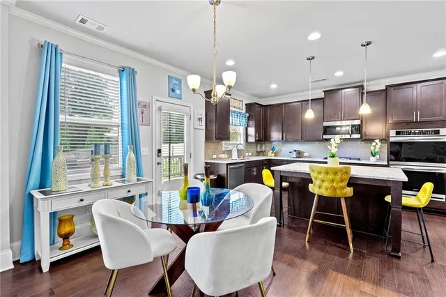 a view of kitchen with stainless steel appliances granite countertop dining table chairs refrigerator and microwave