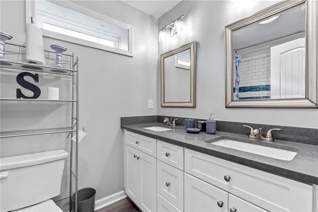 a bathroom with a granite countertop double vanity sink and mirror
