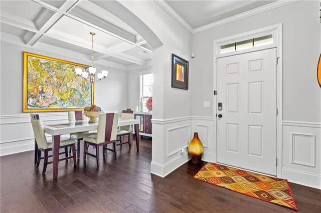 a view of dining room and livingroom with furniture wooden floor a rug a painting and a chandelier