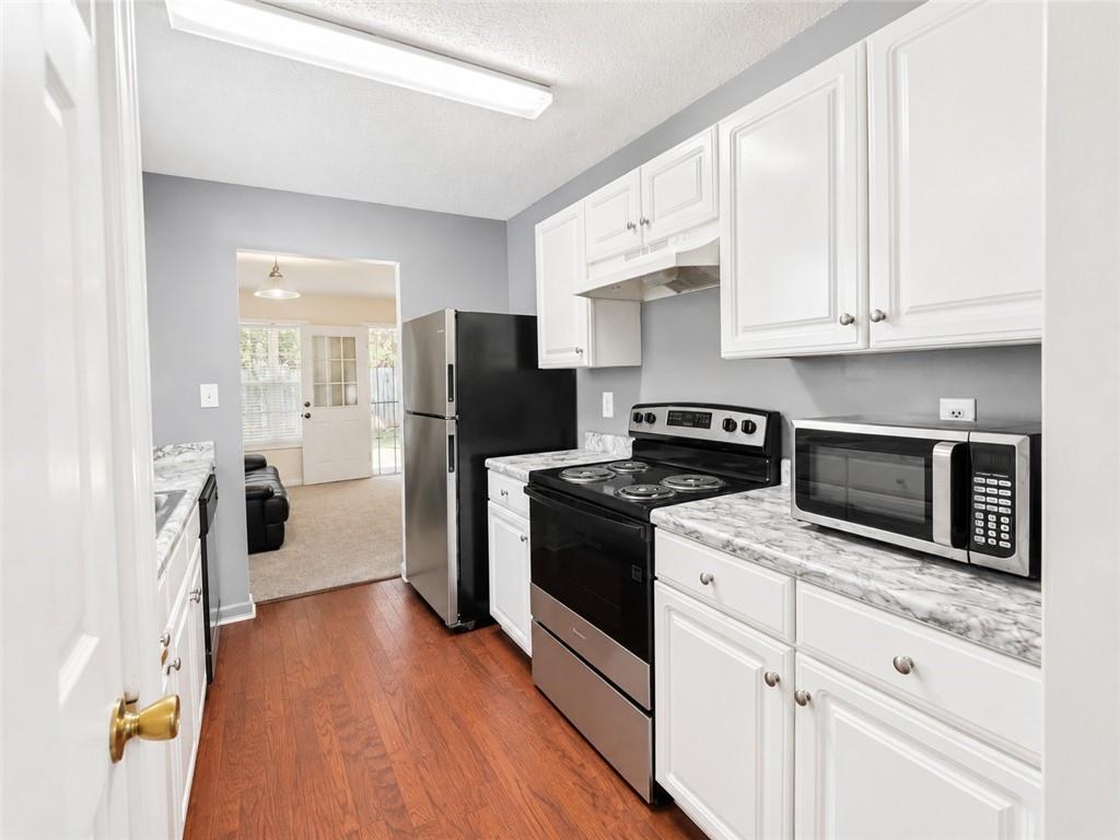 6936 Red Bone Way Stonecrest, GA 30038 - Photo 4 of 17 a kitchen with a refrigerator stove and white cabinets