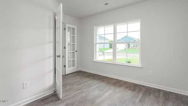 an empty room with wooden floor and windows