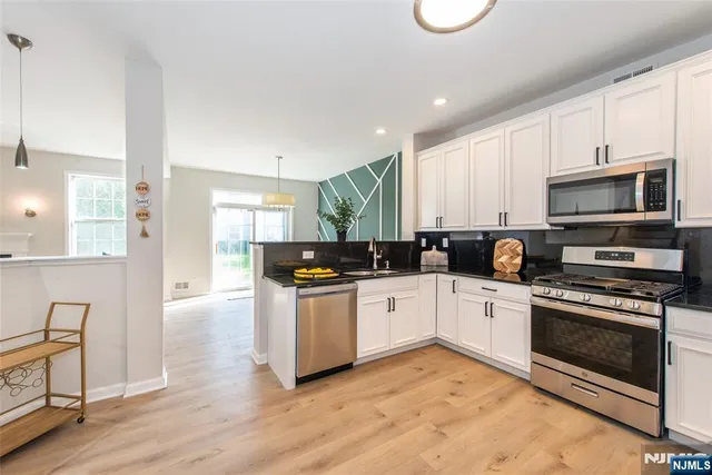 a kitchen with stainless steel appliances granite countertop a stove a sink and a microwave