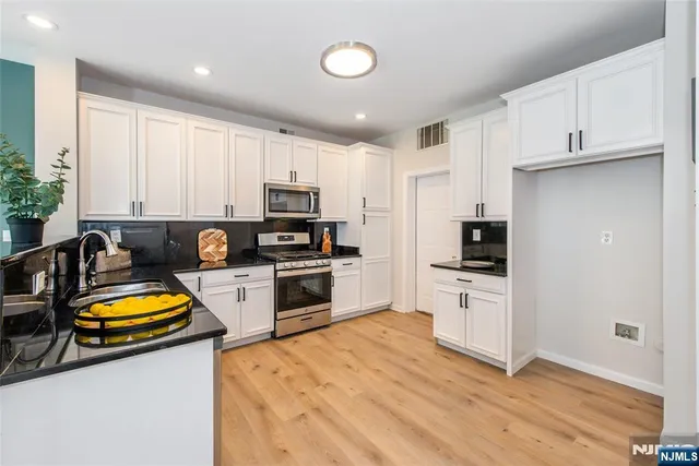 a kitchen with a refrigerator a stove a sink dishwasher and wooden cabinets with wooden floor