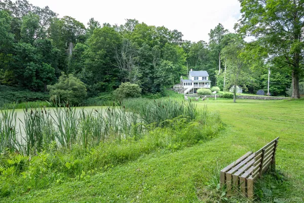 a view of a house with a big yard potted plants and large tree