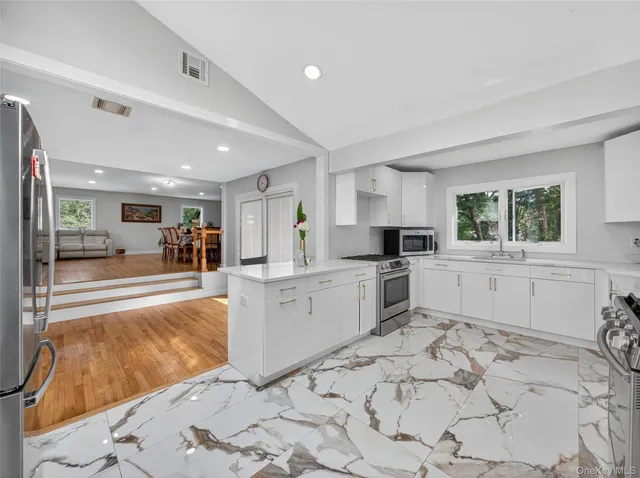 a large white kitchen with a stove a sink a microwave and cabinets