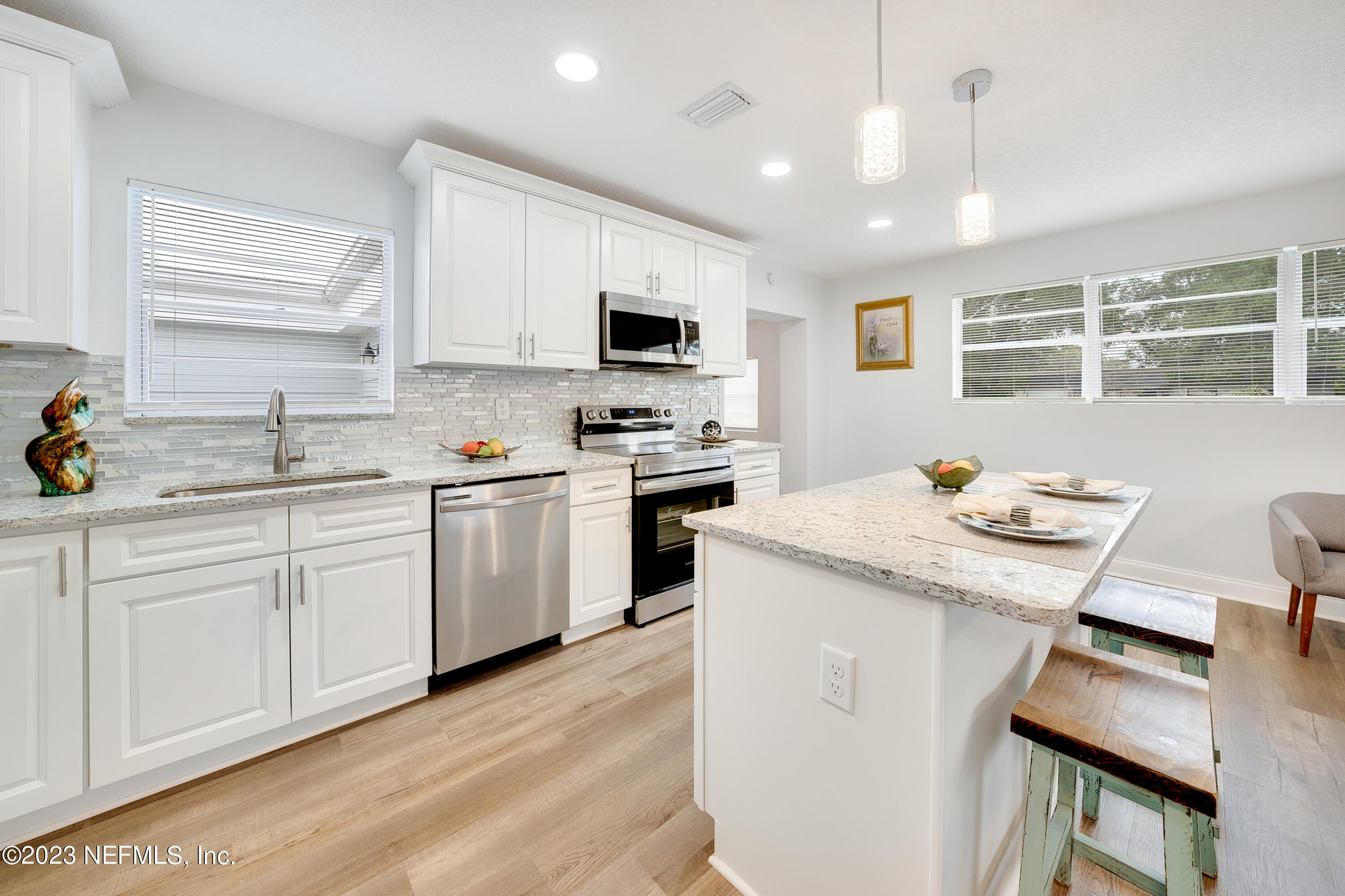 7404 Bamberg Road Jacksonville, FL 32277 - Photo 11 of 31 a kitchen with a stove a sink a microwave a dining table and chairs