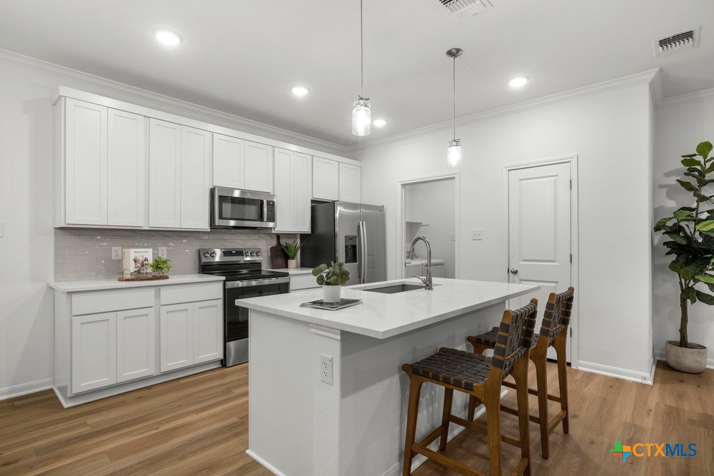 8114 Timber Hollow Lane Temple, TX 76502 - Photo 17 of 34 a kitchen with kitchen island granite countertop a sink stove and white cabinets with wooden floor