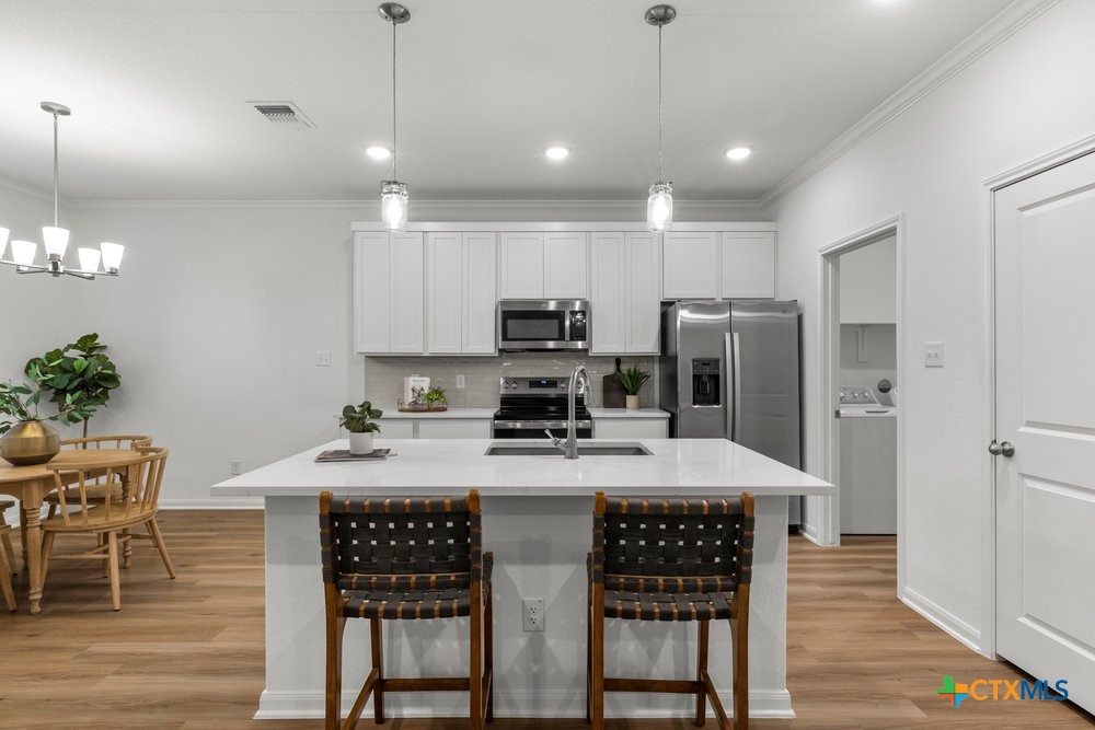 8114 Timber Hollow Lane Temple, TX 76502 - Photo 18 of 34 a kitchen with stainless steel appliances granite countertop a stove refrigerator a table and chairs with wooden floor