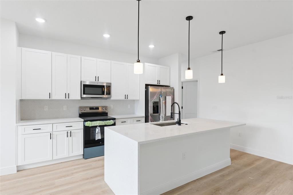 3261 Southwest 129th Loop Ocala, FL 34473 - Photo 11 of 32 a kitchen with stainless steel appliances granite countertop a sink a stove a refrigerator and white cabinets with wooden floor