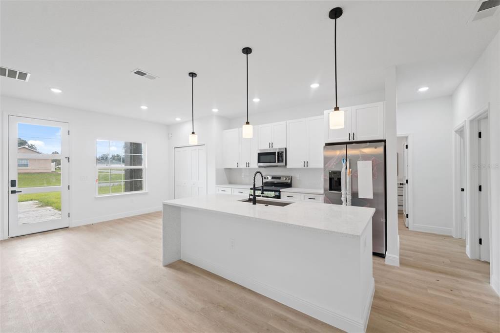 3261 Southwest 129th Loop Ocala, FL 34473 - Photo 13 of 32 a large kitchen with kitchen island a stove a refrigerator a sink a oven and a wooden floor