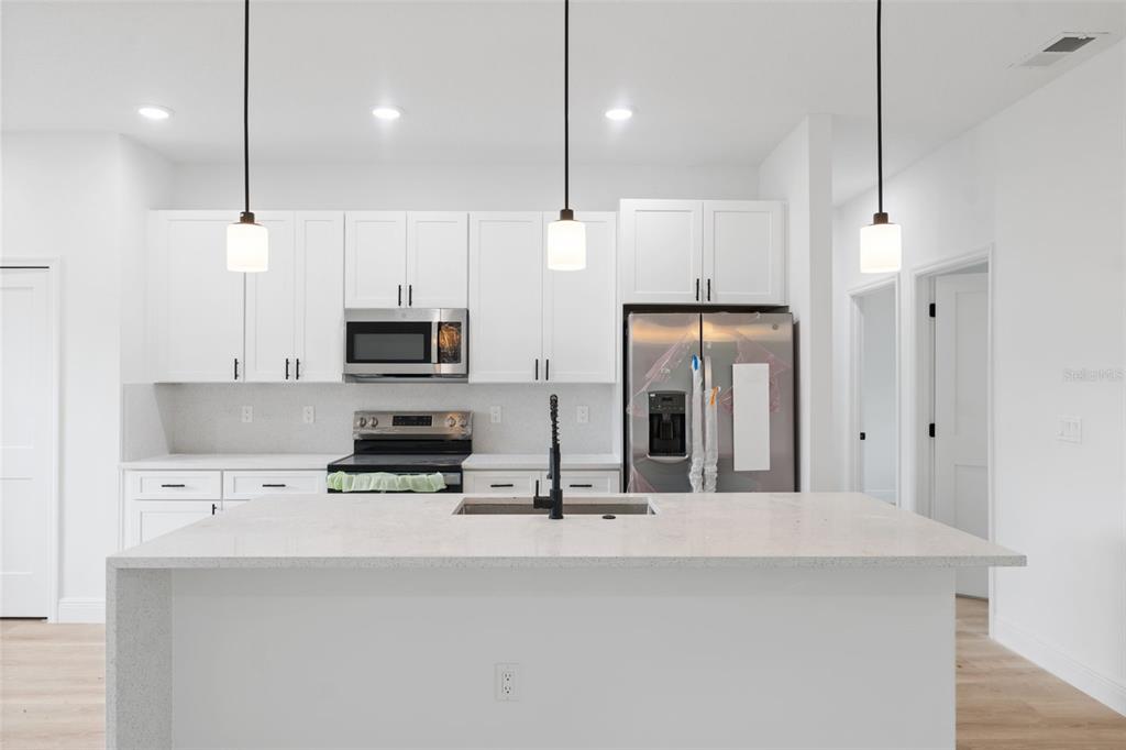 3261 Southwest 129th Loop Ocala, FL 34473 - Photo 10 of 32 a kitchen with kitchen island a refrigerator and a sink