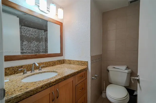 a bathroom with a granite countertop sink a toilet and a mirror