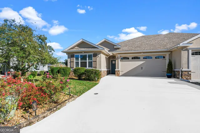 a view of a white house with a yard and potted plants
