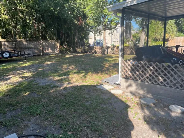 a view of backyard with table and chairs and large trees