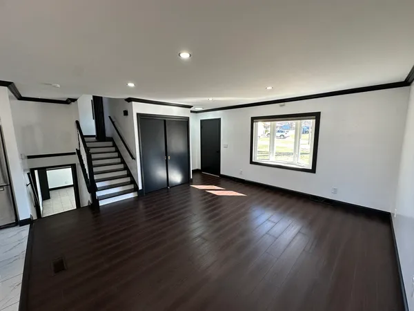 a view of an empty room with wooden floor and windows