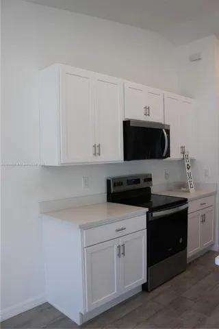 a kitchen with a sink a refrigerator and wooden floor