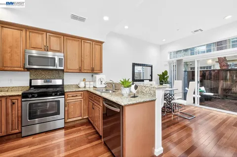 a kitchen with stainless steel appliances granite countertop a stove top oven a sink dishwasher and cabinets with wooden floor