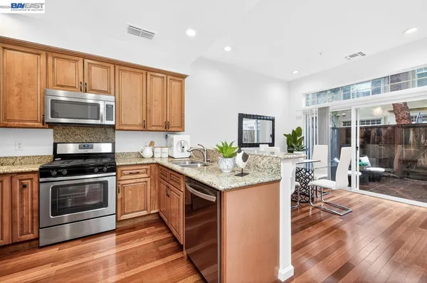 a kitchen with stainless steel appliances granite countertop a stove top oven a sink dishwasher and cabinets with wooden floor