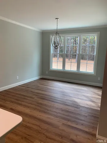 an empty room with wooden floor fireplace and windows