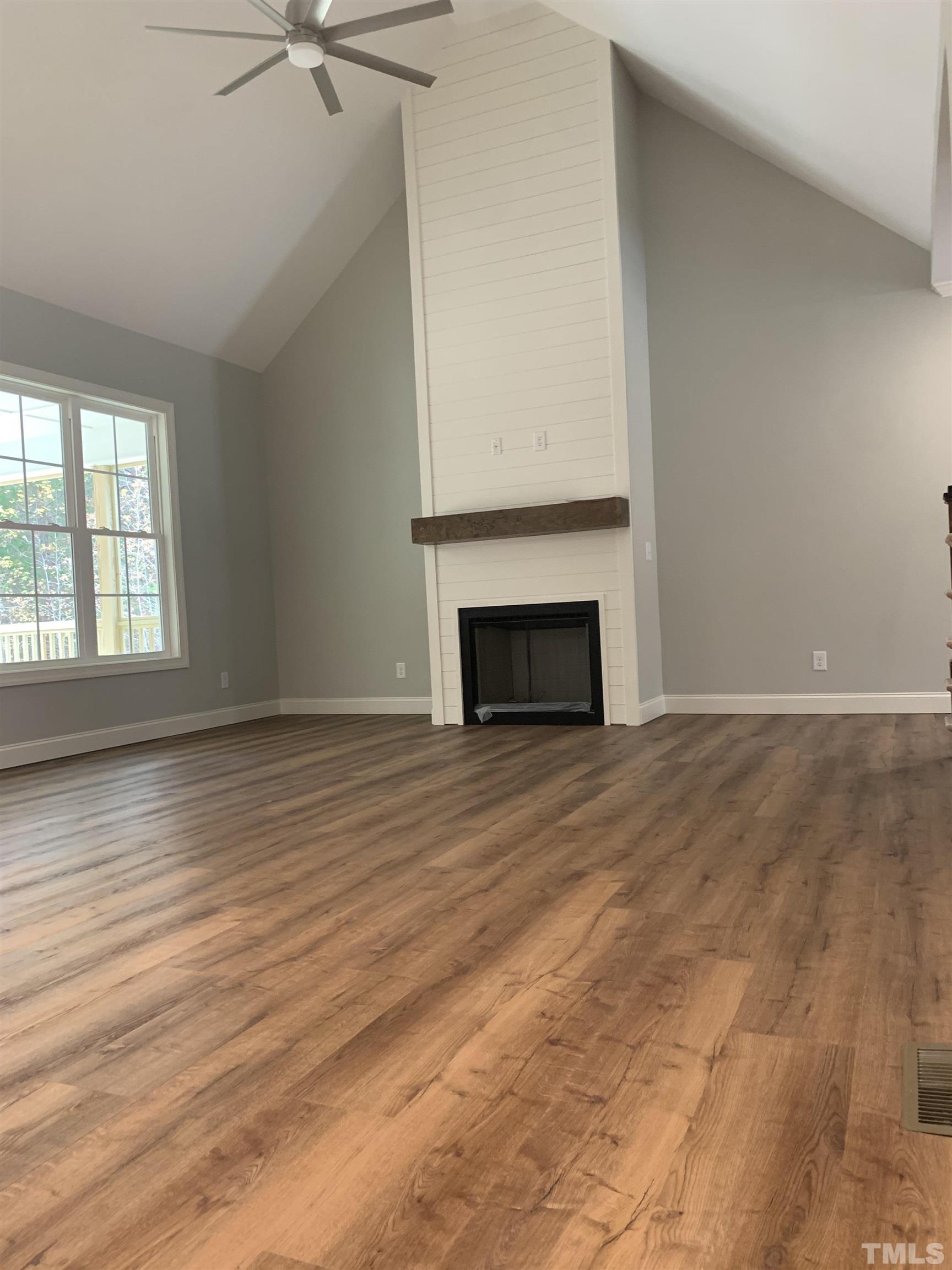 245 Whistlers Cove Louisburg, NC 27549 - Photo 14 of 27 an empty room with wooden floor fireplace and windows