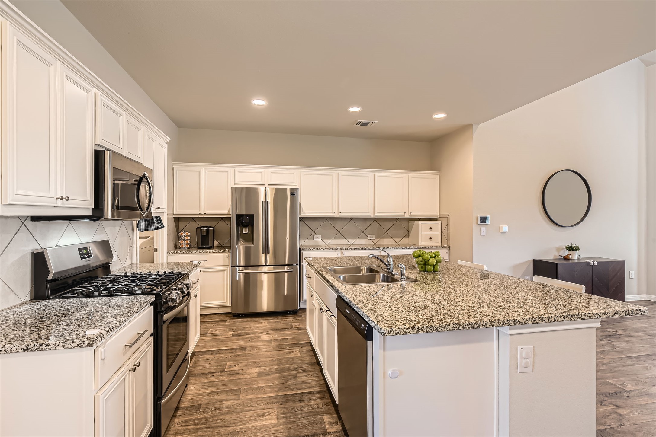 Kitchen featuring visible vents, dark wood finished floors, appliances with stainless steel finishes, white cabinetry, and a sink