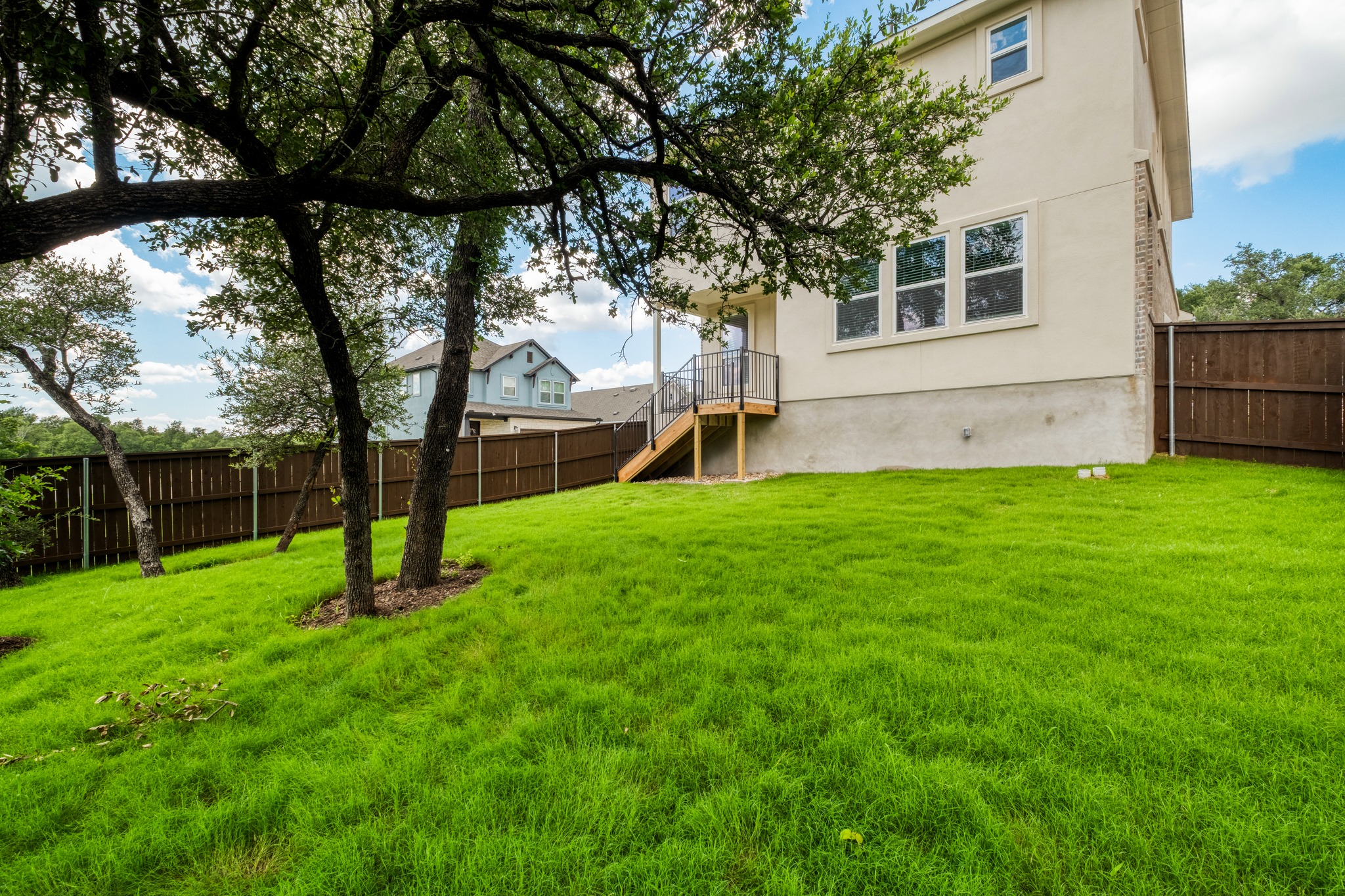 2605 Sam Bass Road, Unit 44 Round Rock, TX 78681 - Photo 26 of 26 A spacious, naturally illuminated private backyard backing to a greenbelt, featuring mature trees and vibrant green grass, perfect for outdoor activities.