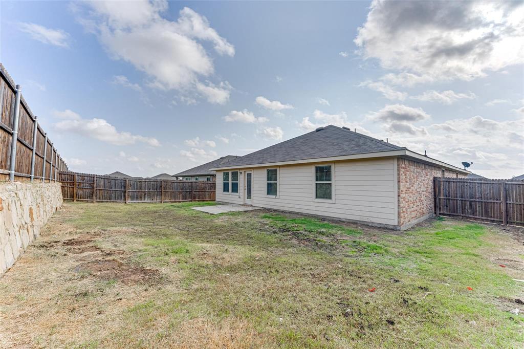 517 Milo Way Royse City, TX 75189 - Photo 23 of 34 Expansive backyard featuring a stone retaining wall, full privacy fencing, a concrete patio, and a combination of brick and siding exterior