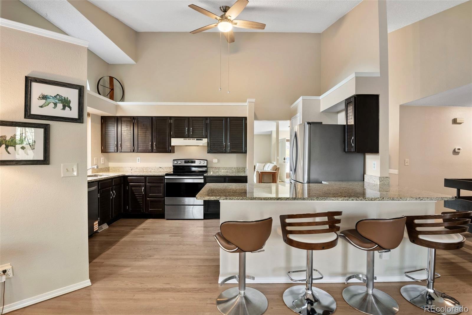 8482 Oak Street Arvada, CO 80005 - Photo 15 of 34 a kitchen with stainless steel appliances kitchen island granite countertop a sink and cabinets