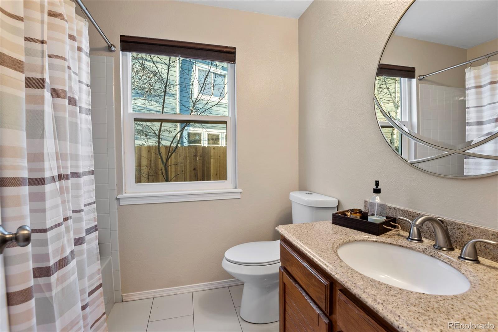 8482 Oak Street Arvada, CO 80005 - Photo 23 of 34 a bathroom with a granite countertop sink a toilet and a mirror