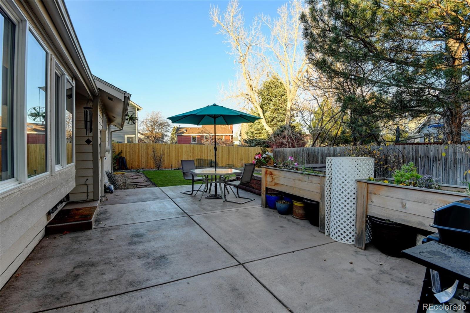 8482 Oak Street Arvada, CO 80005 - Photo 29 of 34 a view of a patio with a table and chairs under an umbrella with a small yard