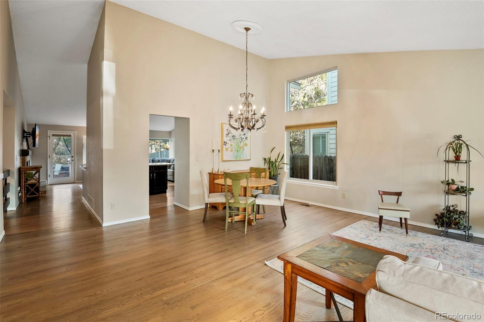 8482 Oak Street Arvada, CO 80005 - Photo 3 of 34 a dining room with wooden floor a chandelier a wooden table and chairs
