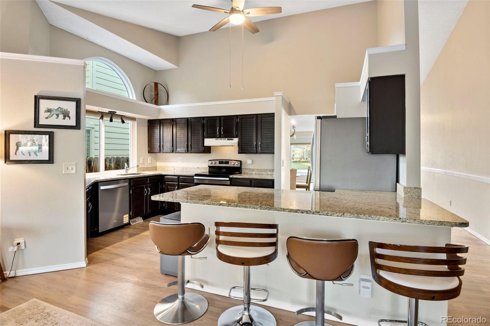 8482 Oak Street Arvada, CO 80005 - Photo 8 of 34 a kitchen with stainless steel appliances granite countertop a stove top oven a sink dishwasher a dining table and chairs with wooden floor