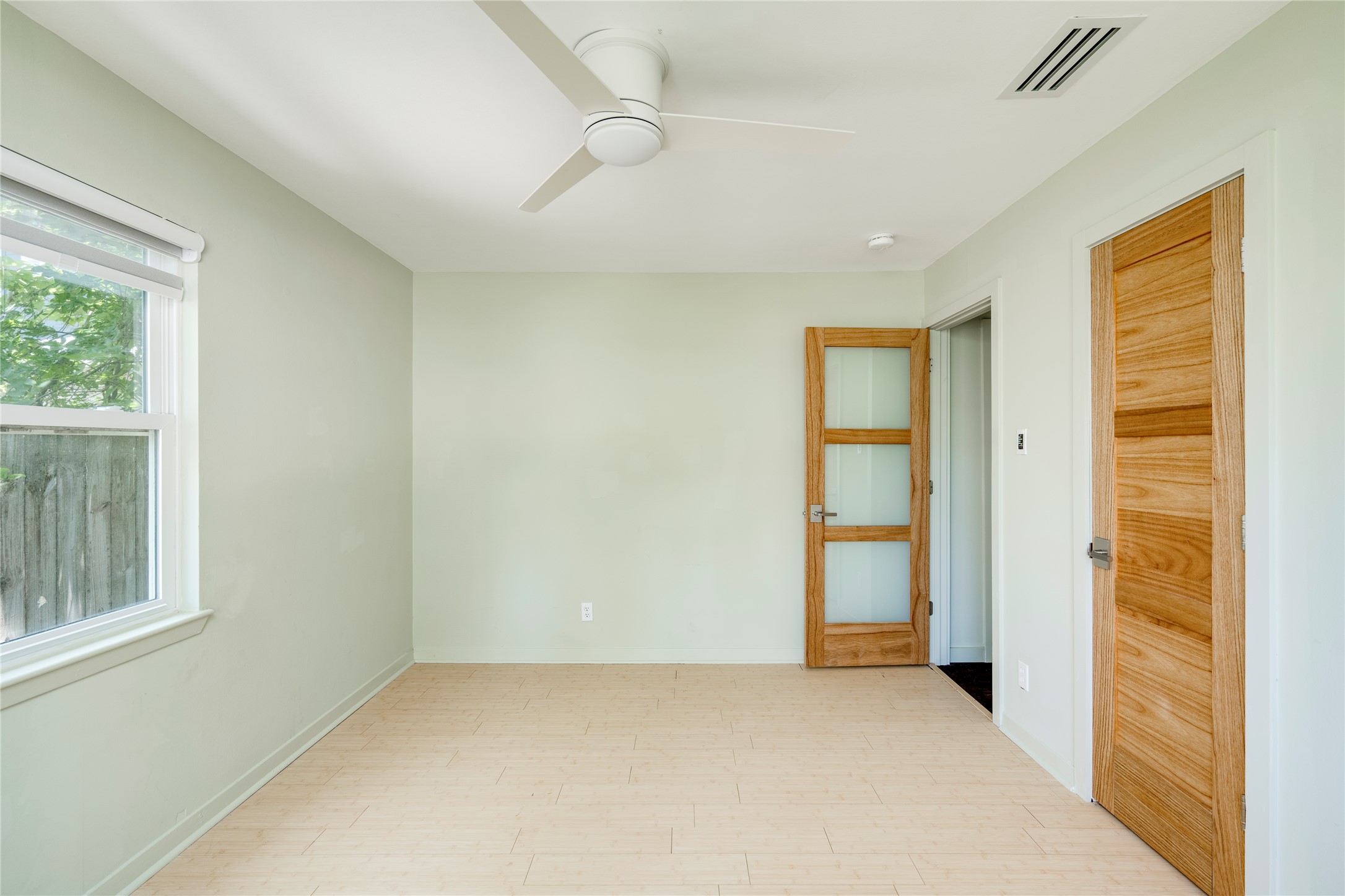 1707 Overhill Drive Austin, TX 78721 - Photo 17 of 36 A quiet bedroom with a modern ceiling fan, bright window, and light wood flooring.