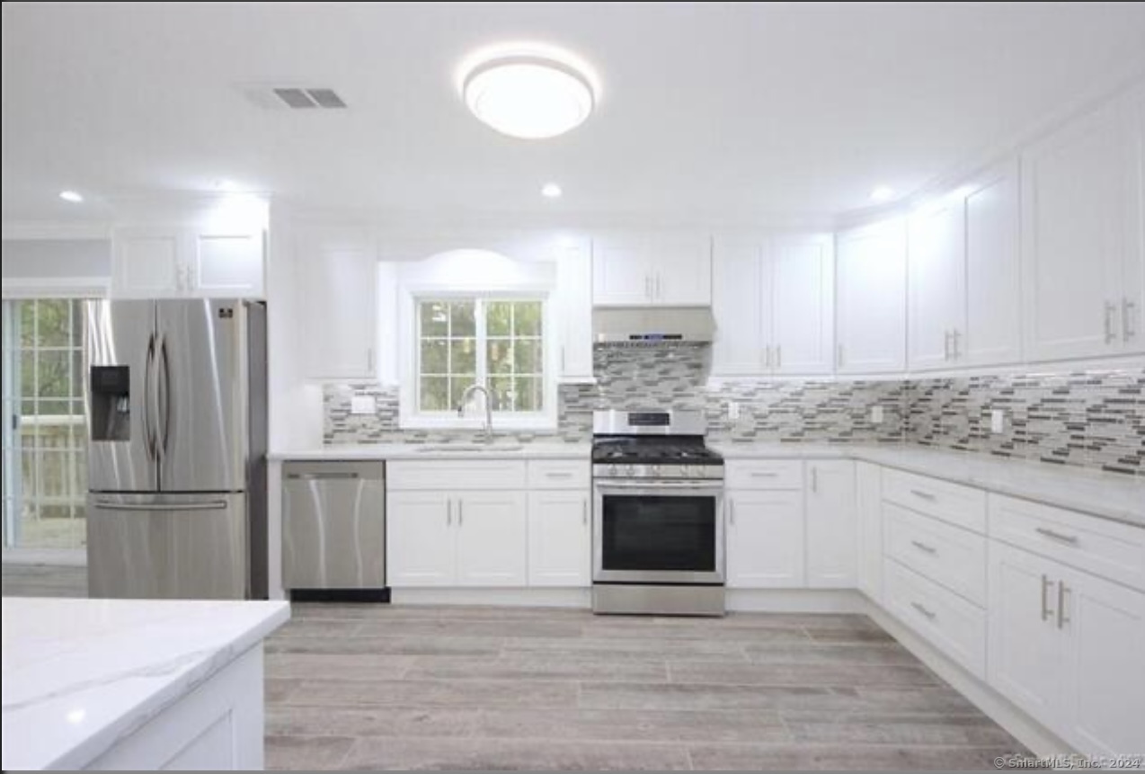 a kitchen with granite countertop a refrigerator stove top oven and sink