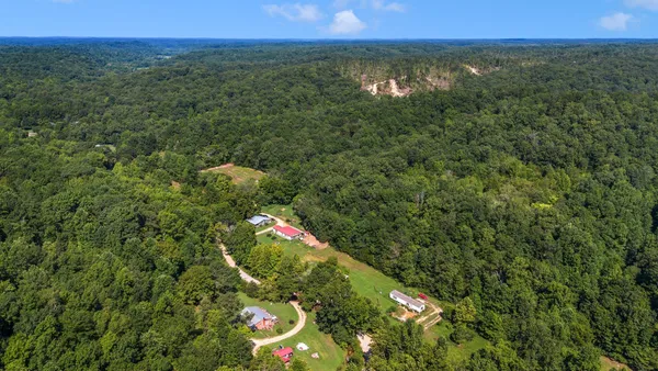 an aerial view of residential house with outdoor space and trees all around